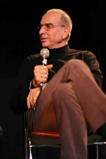 a man in black suit and brown pants holding a microphone
