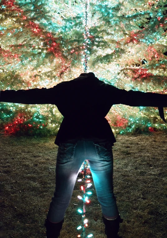 a person standing in front of christmas lights at night