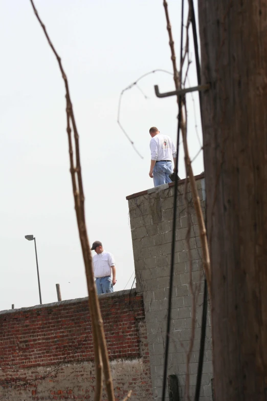 two men are standing on the roof while one watches the other