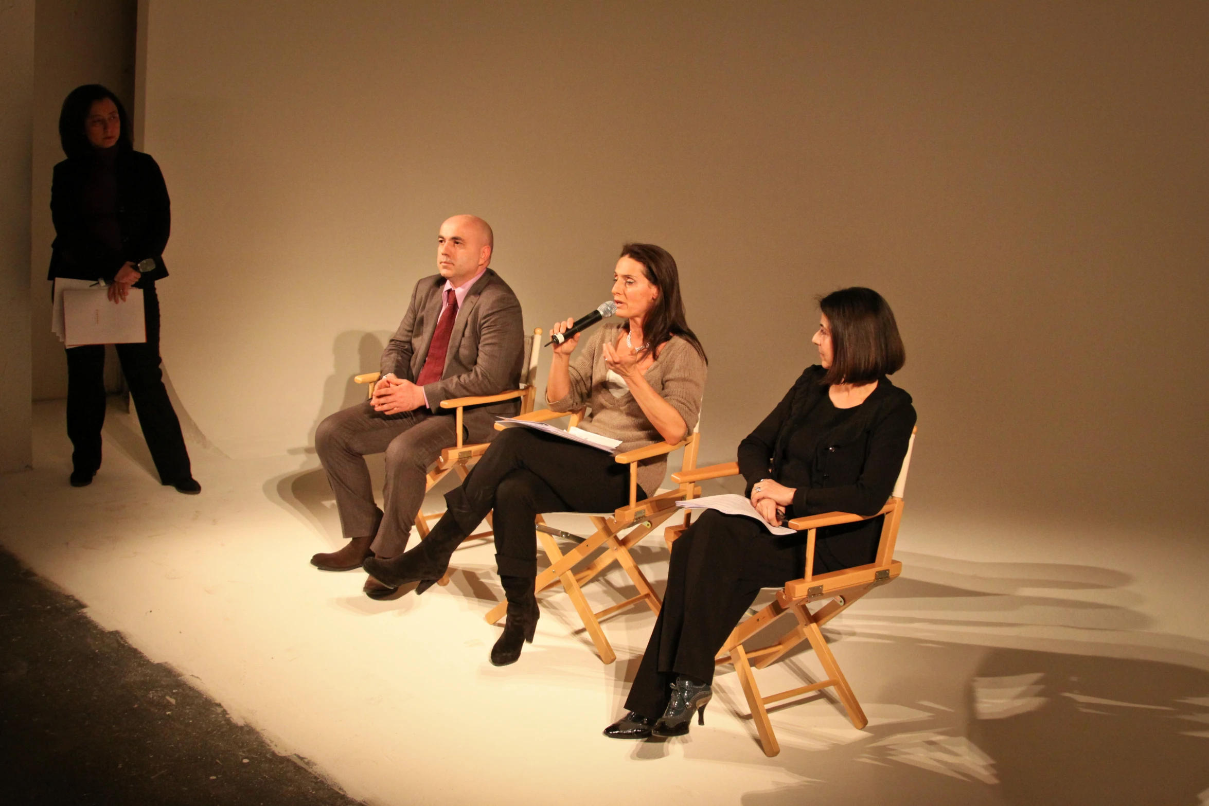 three people sitting in wooden chairs at a podium