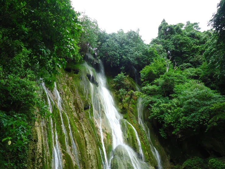 people are standing near a waterfall on the water