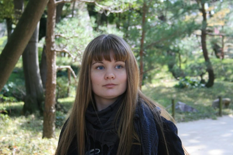 the girl stands alone in a tree - lined park