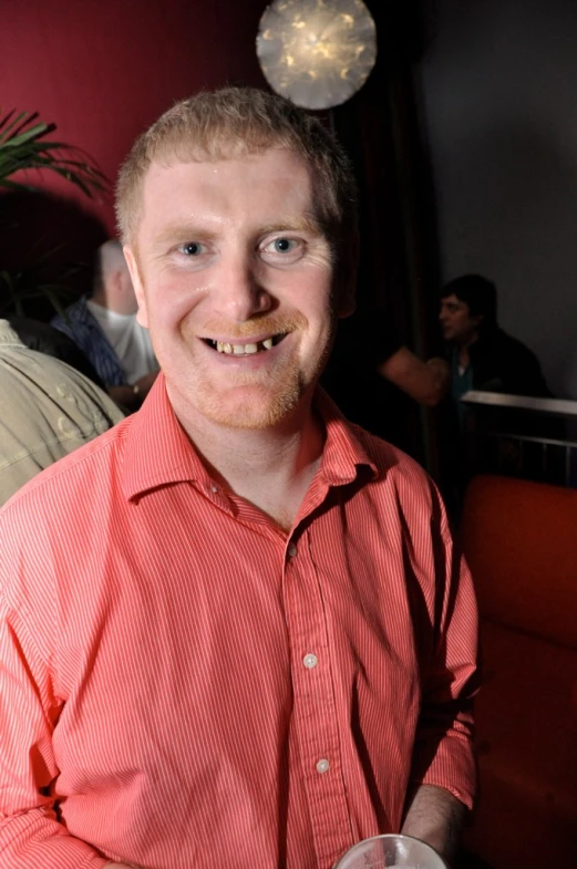 a man wearing a red shirt and holding a wine glass