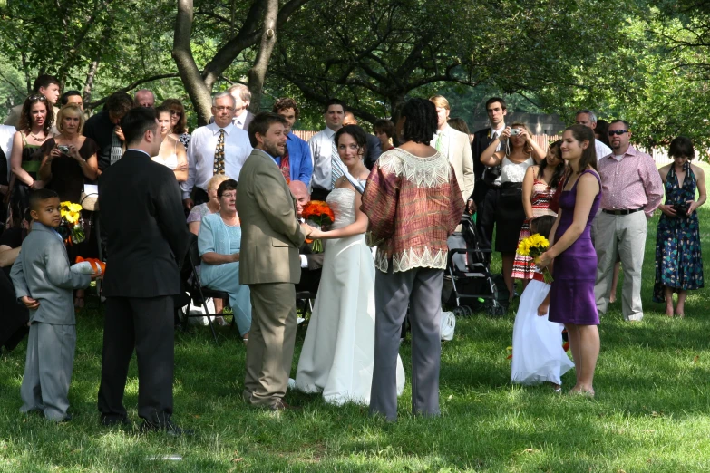 a wedding ceremony outside under trees with lots of people
