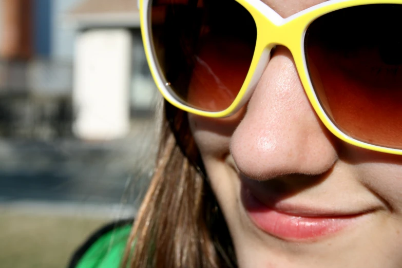 the woman is wearing a yellow sunglasses near the tree