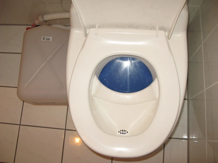 a white toilet with a blue window and tile walls