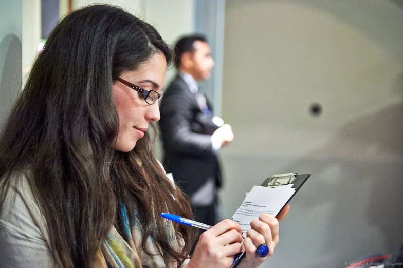 young woman with long hair holding pencil while checking paperwork