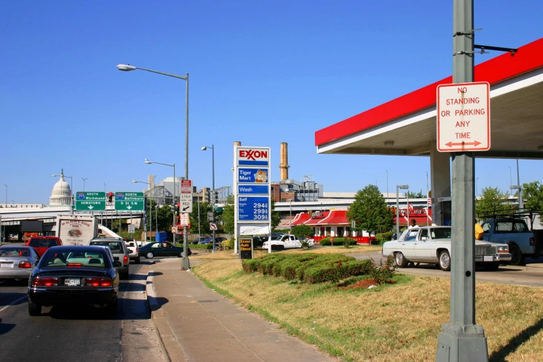 a row of gas pumps and cars near some stores