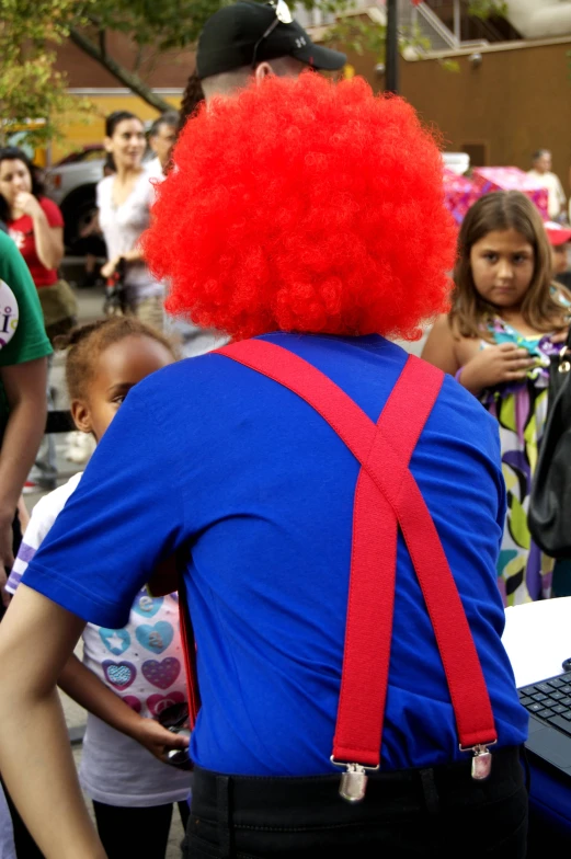 a young man in clown mask and red wig with others behind him