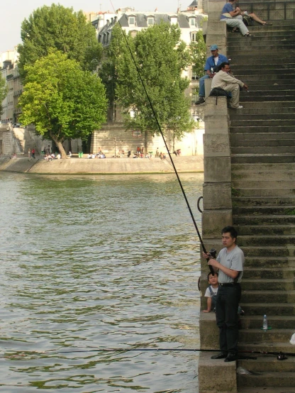 a boy standing on the steps holding a fish while another man holds onto it