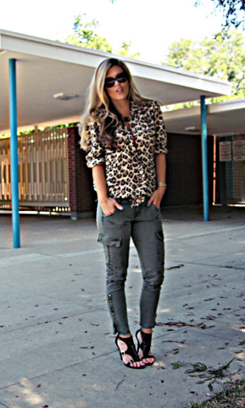 a woman stands near a parking lot in a leopard top