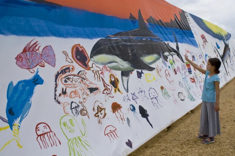 a young person near a huge mural on the wall