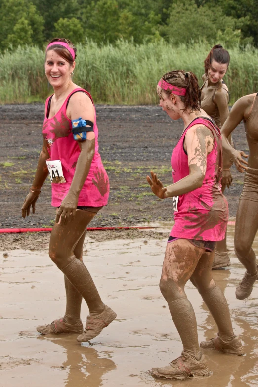 the people in pink vests are covered with mud