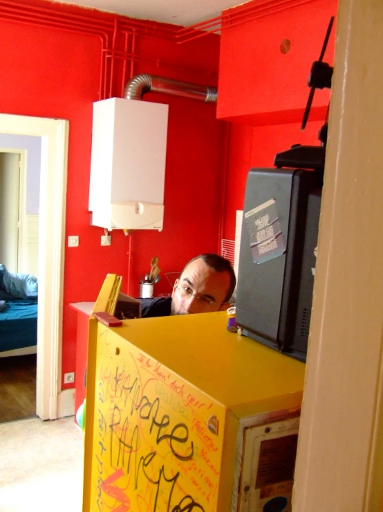 a man in a red room behind a yellow counter