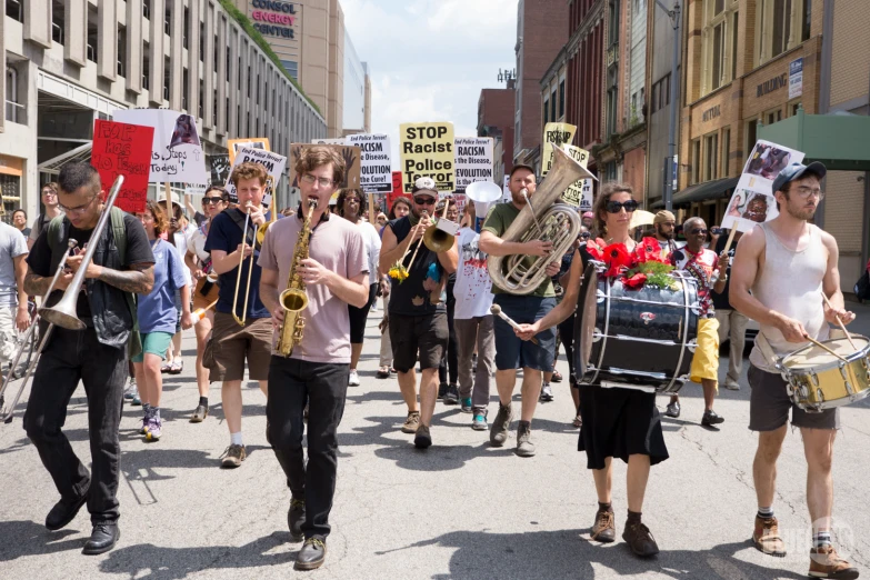 people carrying signs and holding musical instruments are marching