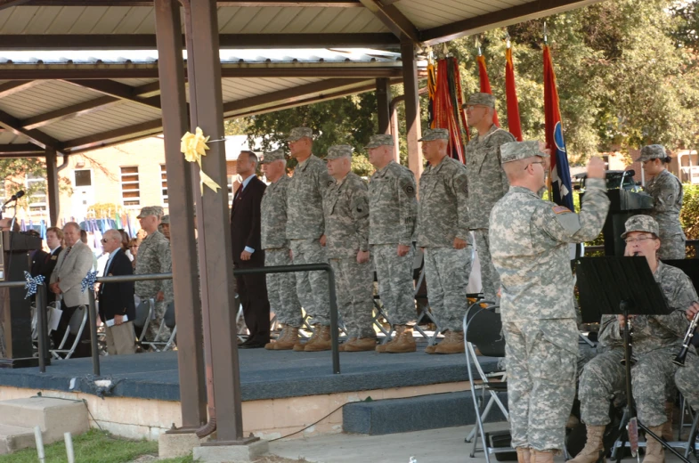 men and women in uniforms stand on a stage while others watch