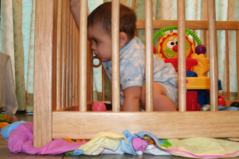 a baby sitting on the ground in front of a cage