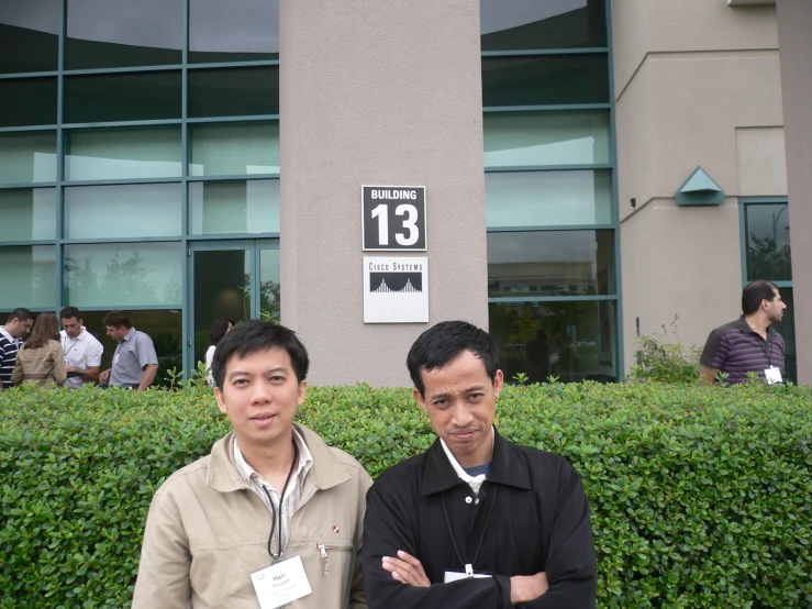 two men in front of some hedges and signs