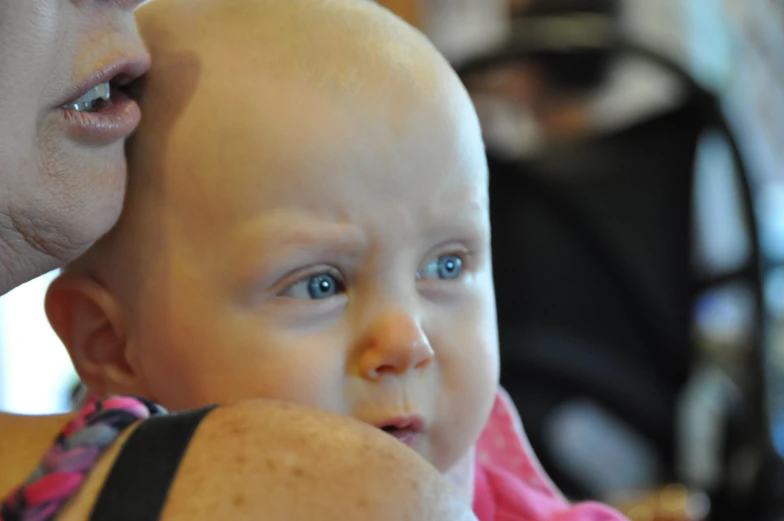 a woman with a bald head holds her infant