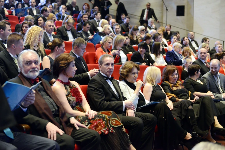 people in a conference sitting in rows and some in dresses