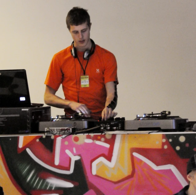 a dj in an orange shirt works on some records