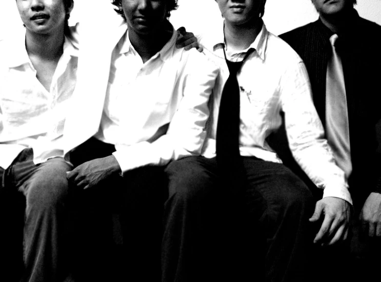 black and white po of four men in dress shirts