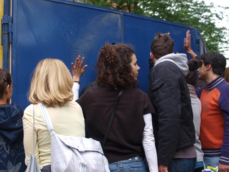 a group of people standing next to a blue trailer