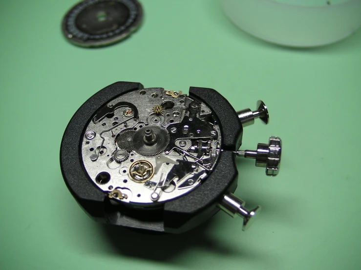 a black watch movement that is close up on a green table
