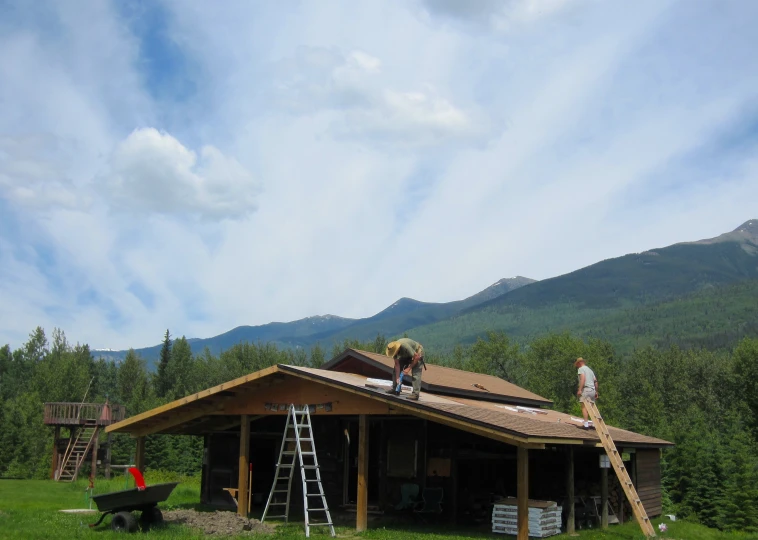 men are repairing the roof of a small cabin