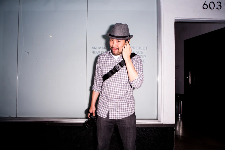 a man talking on his cell phone next to a tall wall