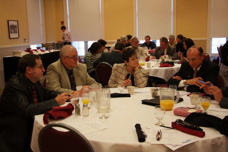 several people are seated at tables with their cell phones