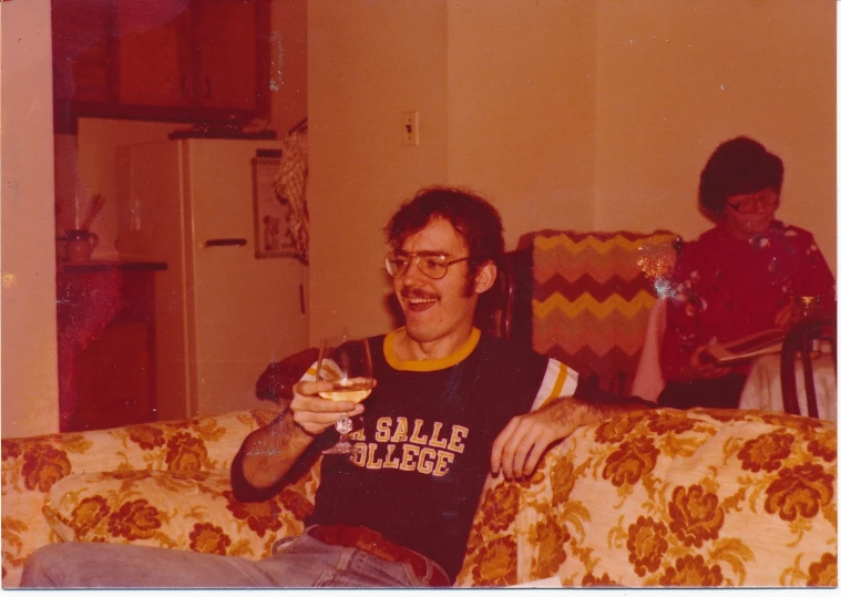 two people sitting on a couch with one person holding a bottle