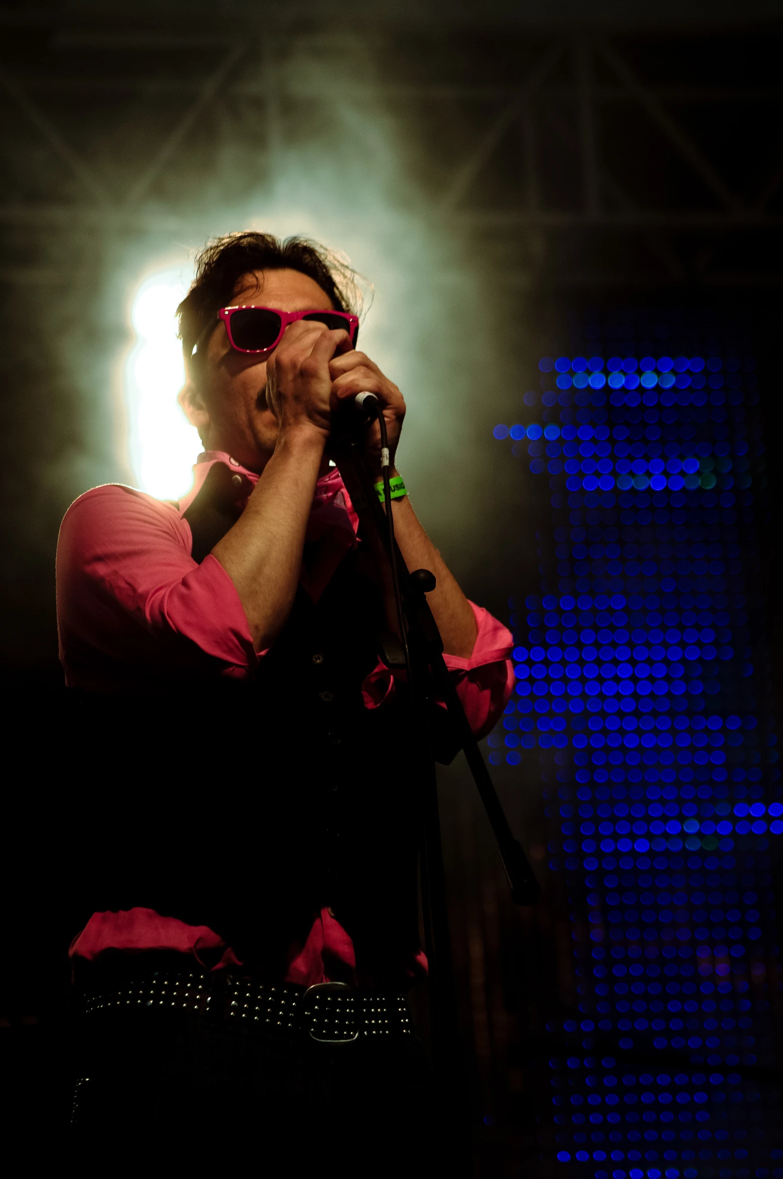 a man wearing sunglasses is singing on stage