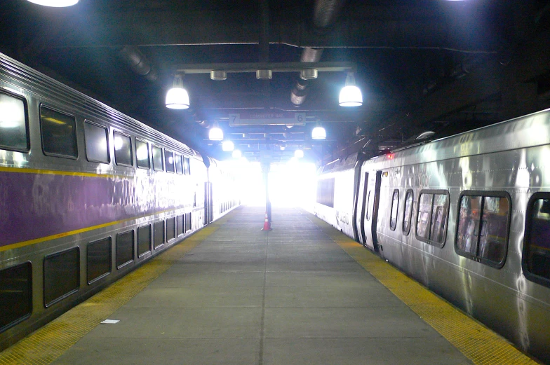 a long train station with two trains side by side