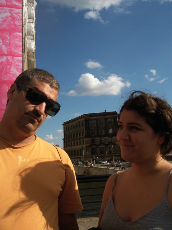 a man and a woman standing near buildings and a pink building