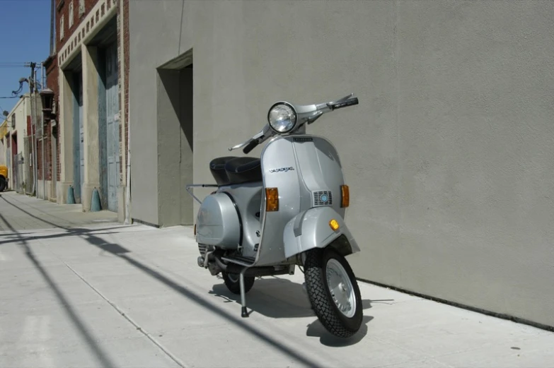 a silver motorbike is parked on the sidewalk