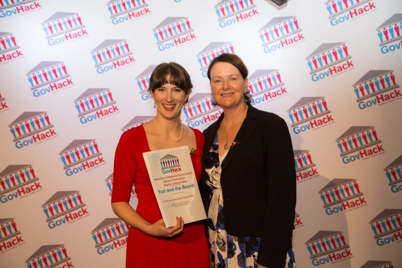 two women standing next to each other and holding an award plaque