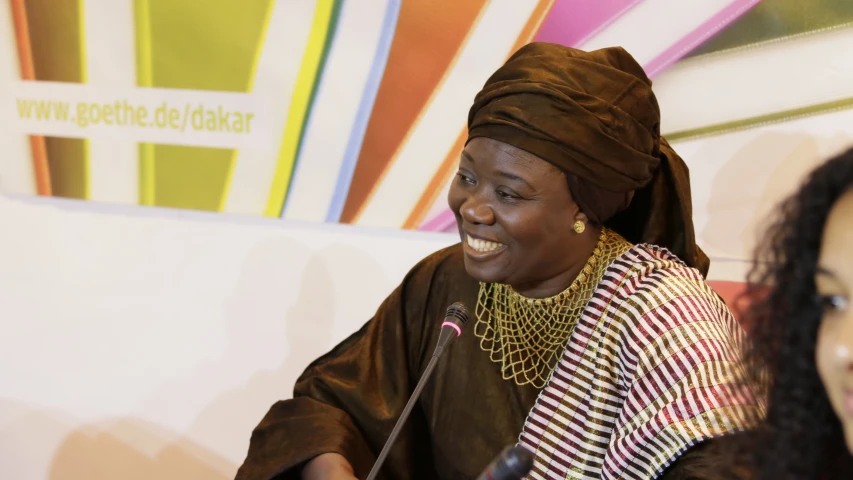 a woman is sitting at a microphone and smiling