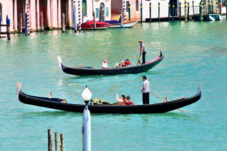 gondolas in the water with people rowing them
