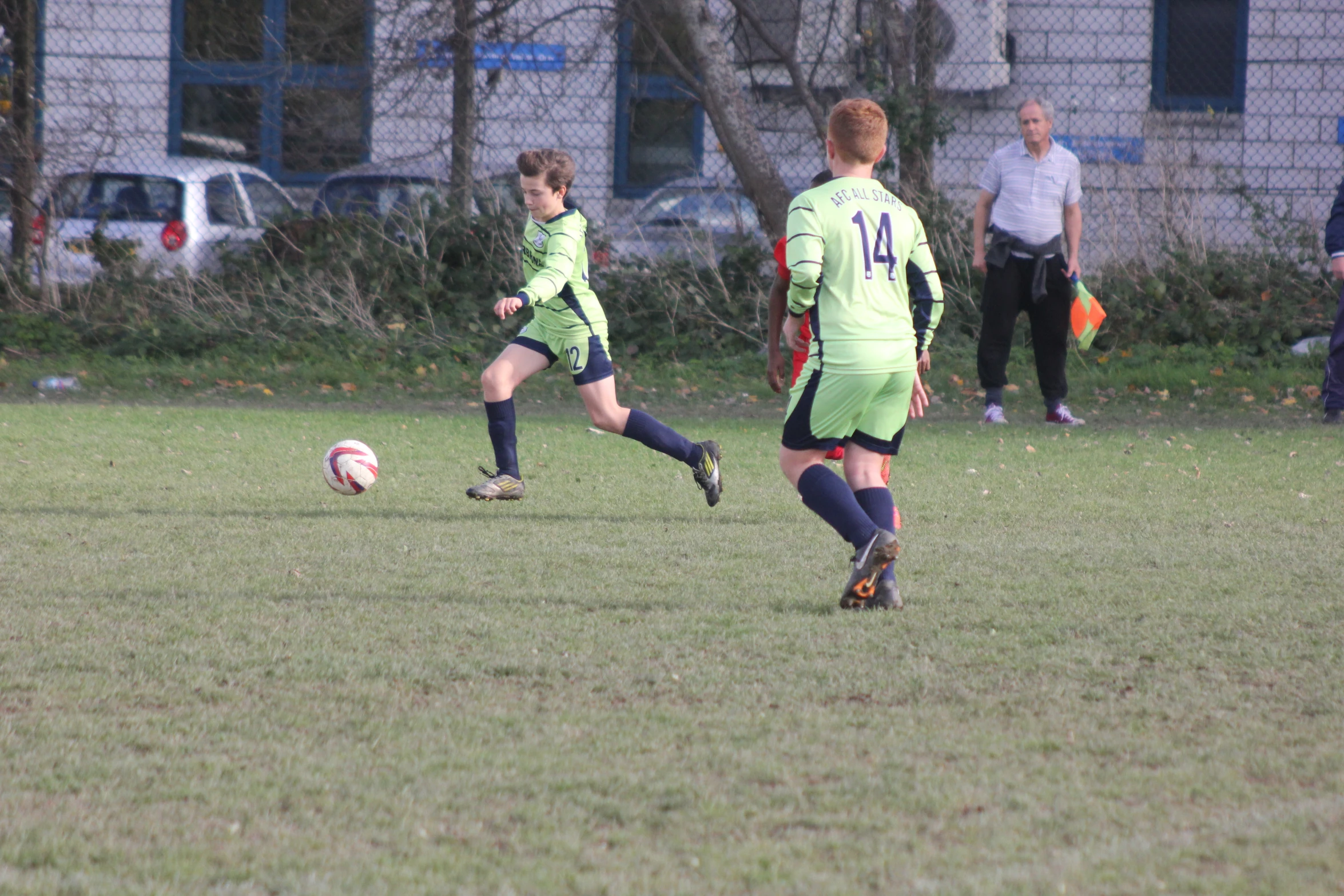 two children running after a soccer ball in a soccer field