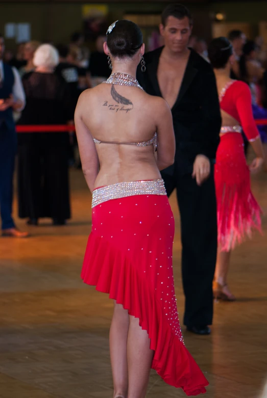 a woman wearing a red dress in front of other people