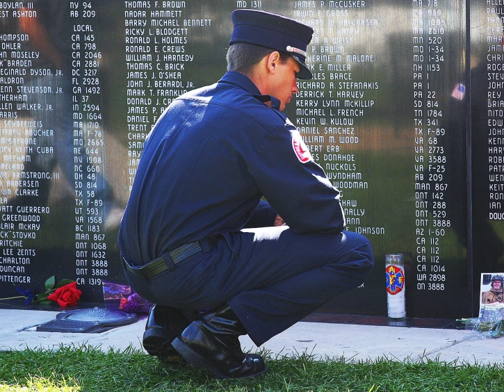 a man in uniform squatting in front of a war memorial