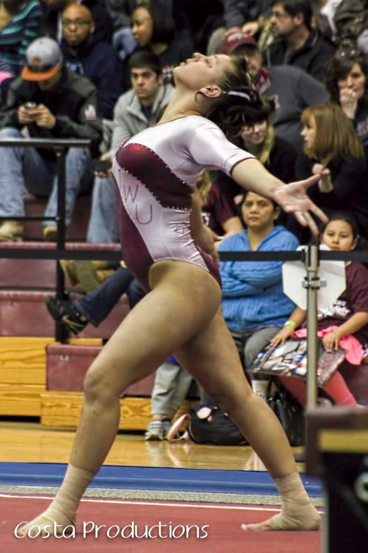 a woman is doing gymnastics, and a man stands behind her