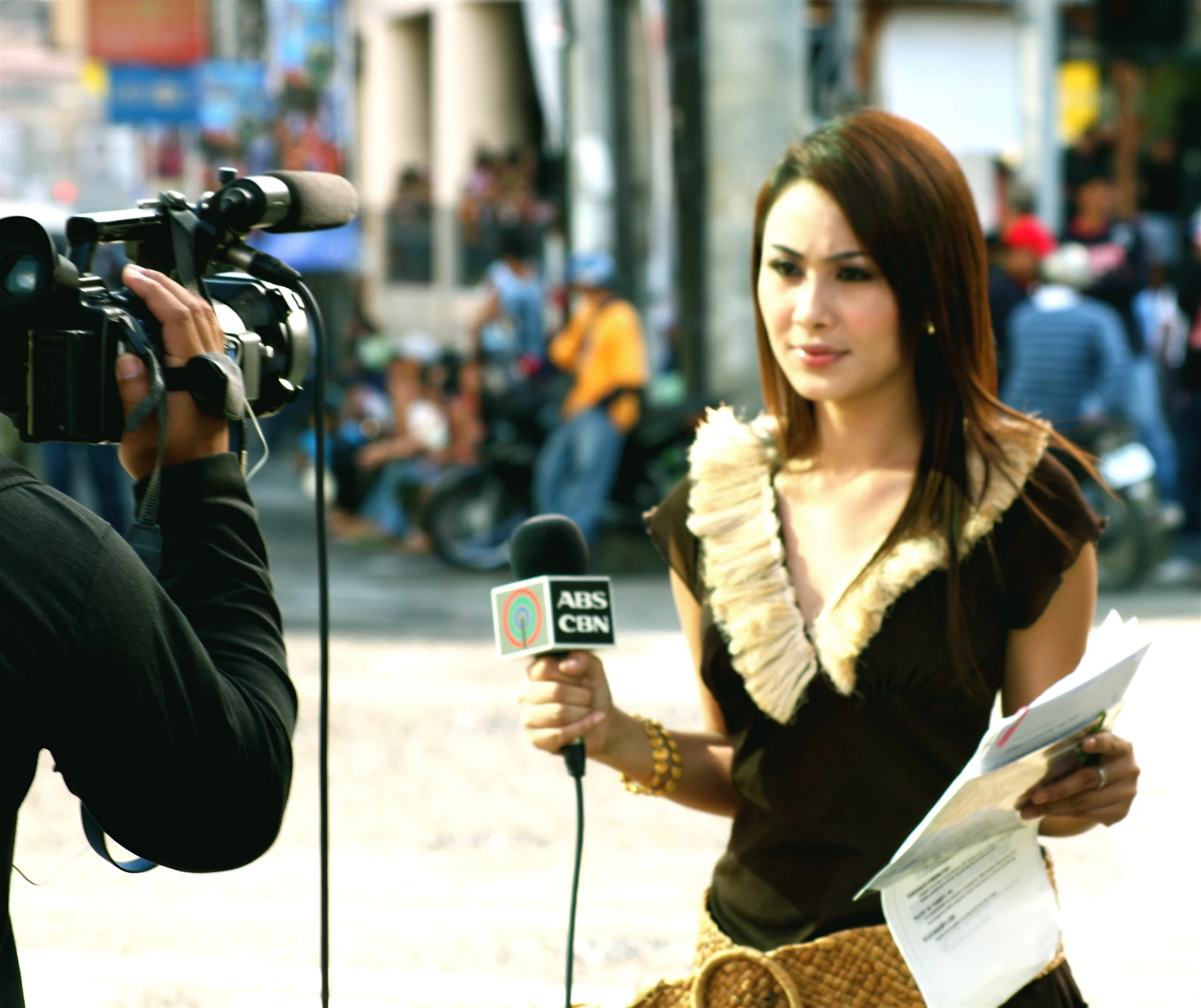 a female wearing a brown top is holding a microphone
