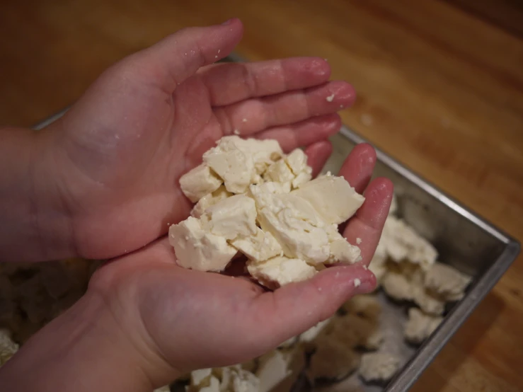 someone is holding out their hand with some cottage cheese