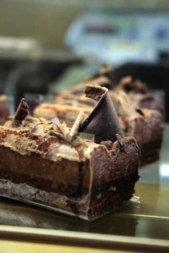 three dessert bars with chocolate on them in a display case