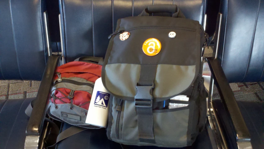 a backpack, bottle and other travel accessories sitting on a chair