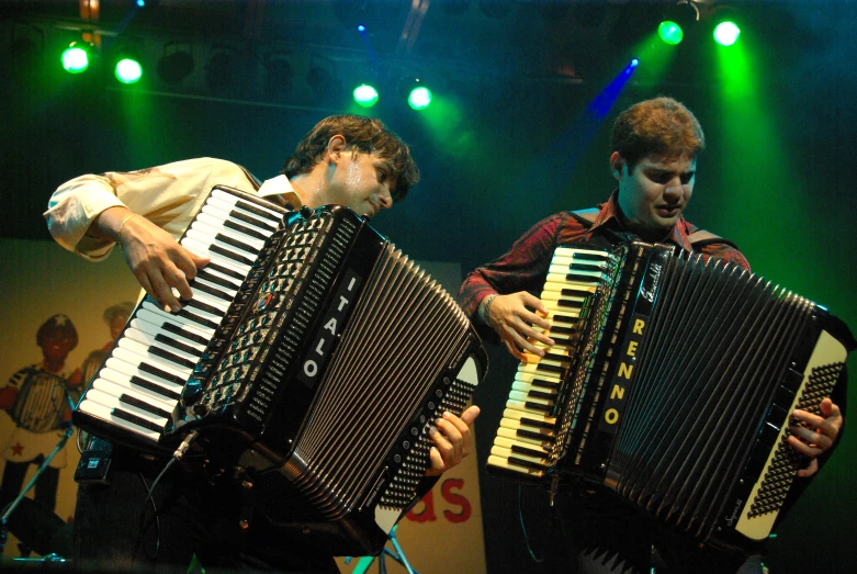 two men are holding an accordion and wearing gloves