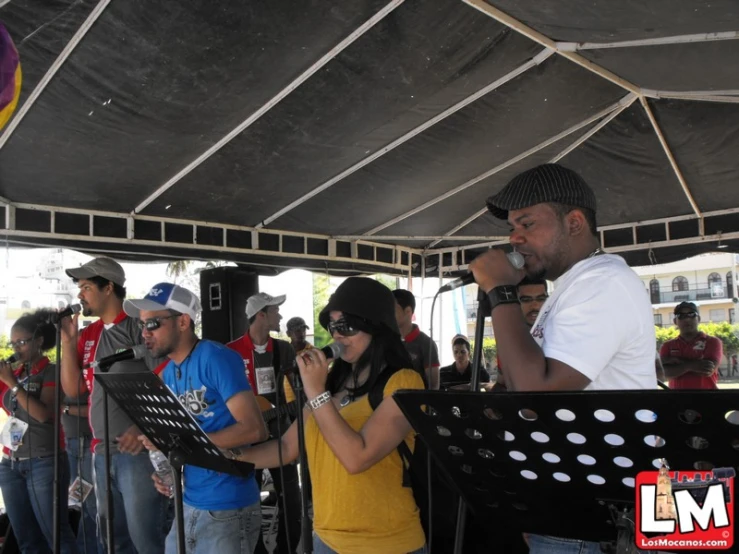 the man is singing into a microphone while others watch