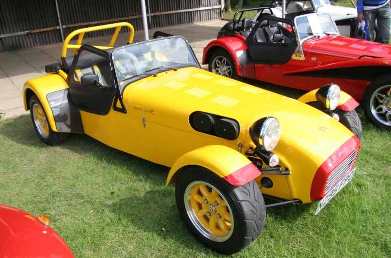 a yellow sports car parked on the grass next to another red sports car